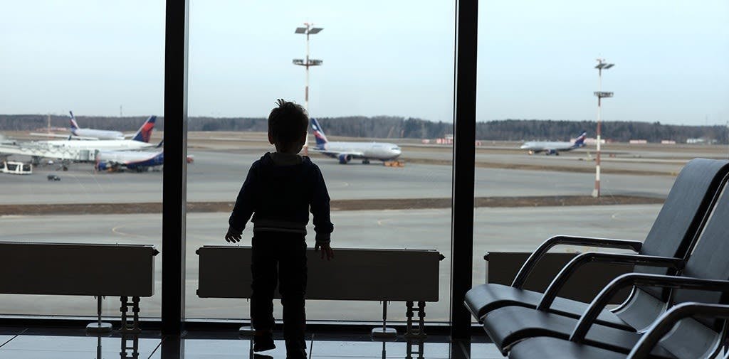 Silhouette of a child looking out an airport window