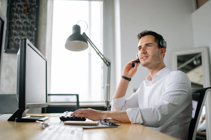 Man at desktop and phone providing support