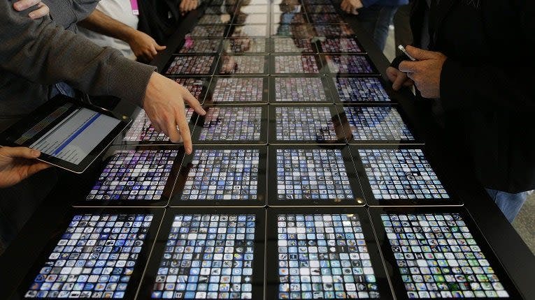 A long table full of tablets with people standing around it