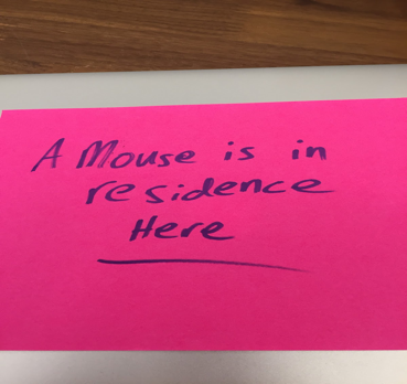 A pink post-it note reading "A mouse is in residence here"