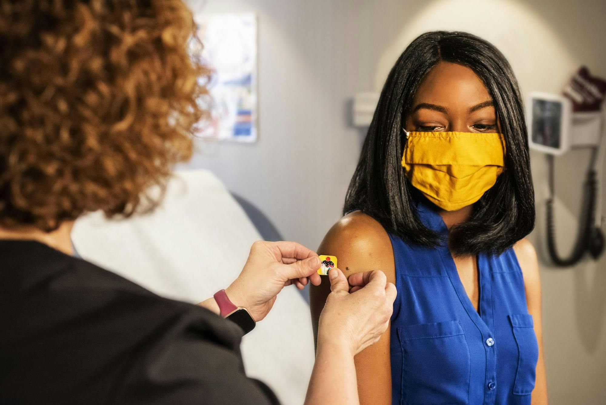 A young black woman in blue shirt receiving a vaccination