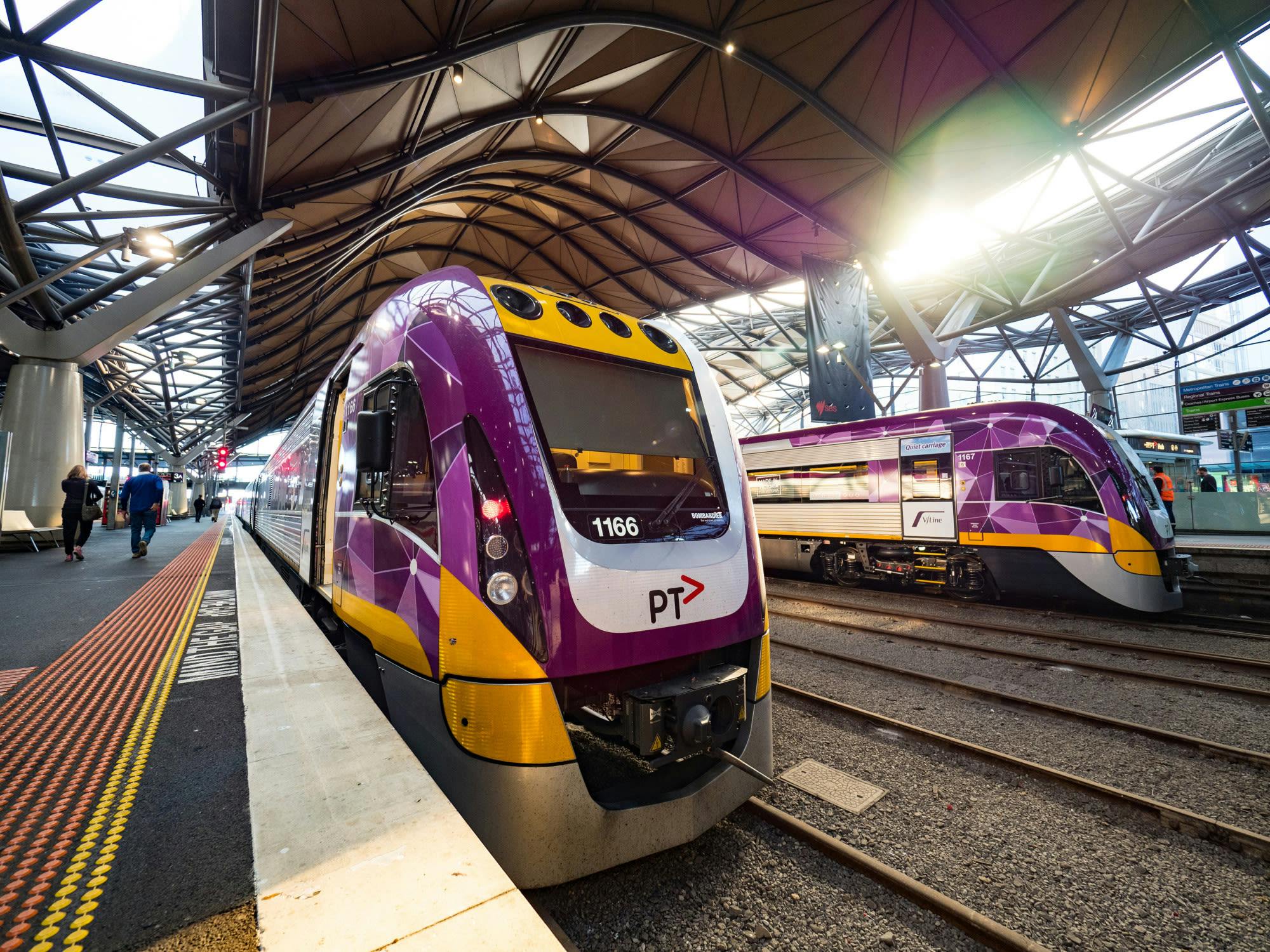 Two purple and yellow passenger trains parked in a station