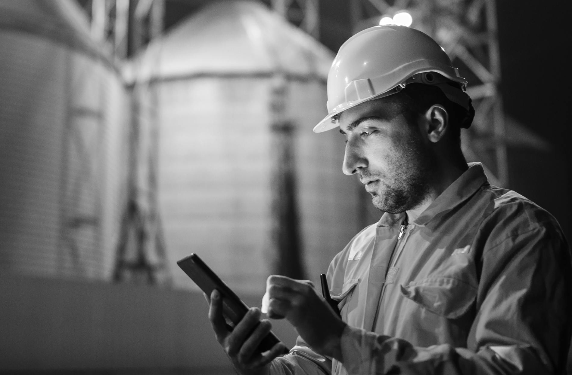 Male worker with hard hat looking at the phone to illustrate energy and utilities solution